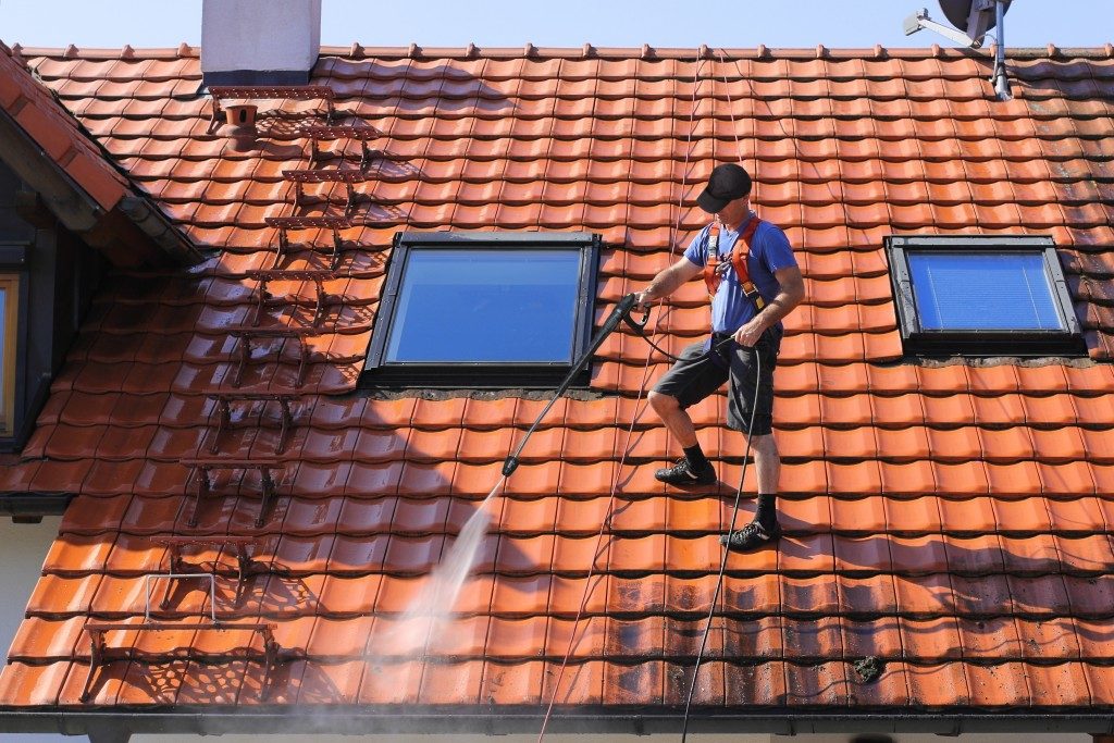 Man cleaning roof with high pressure water