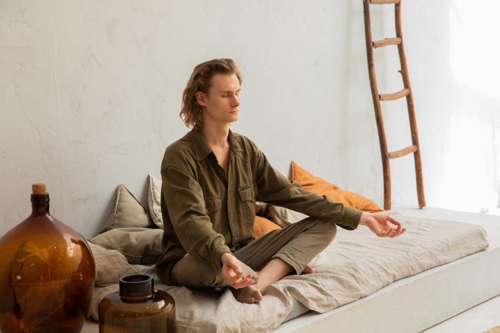 man meditating on his bed